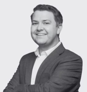 Black and White Headshot of Jake Hindley. Arms crossed